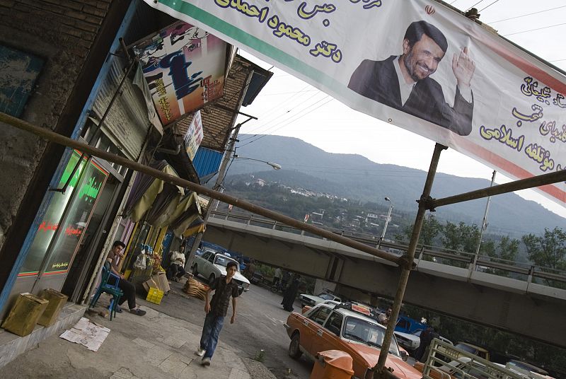 Un joven camina bajo uno de los carteles electorales del actual presidente, Mahmud Ahmadineyad