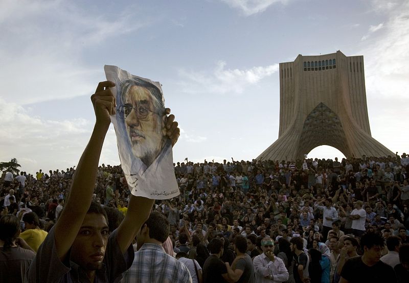 Un manifestante alza una imágen de Mousavi, cerca del monumento de la plaza de Azadi.