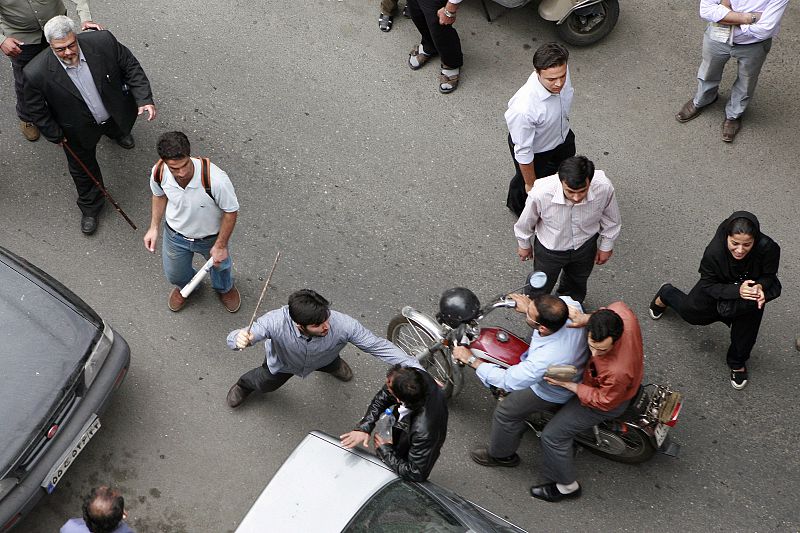 Un hombre iraní a palazos contra un hombre durante las protestas en Tehran.