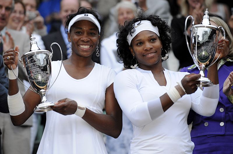 Serena and Venus Williams of the U.S. hold their trophies after defeating Lisa Raymond of the U.S. and Samantha Stosur of Australia in their doubles finals match at the Wimbledon tennis championships in London