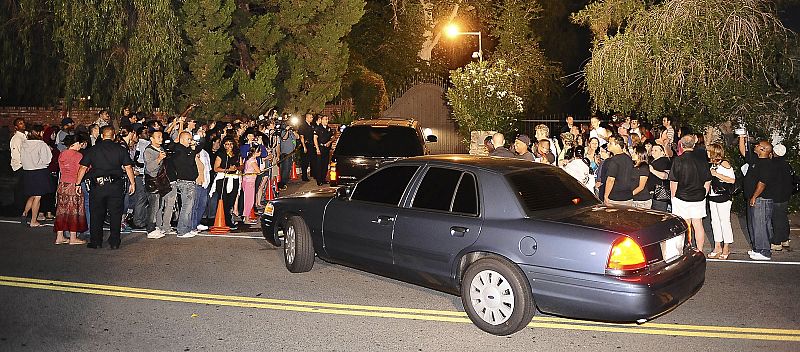 Una comitiva de coches pasa entre los fans congregados a las puertas de la residencia de la familia Jackson.