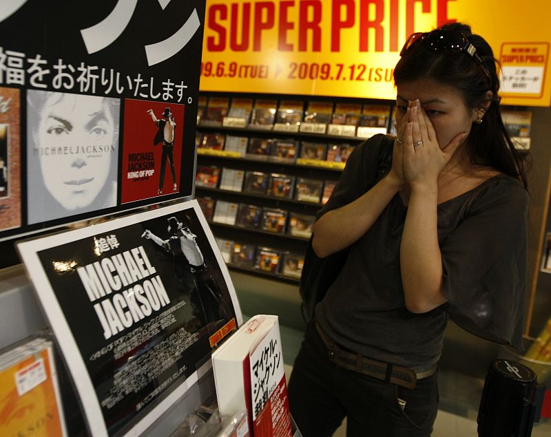 Una fan japonesa entristecida mira un mostrador conmemorativo en una tienda de música en Tokio.