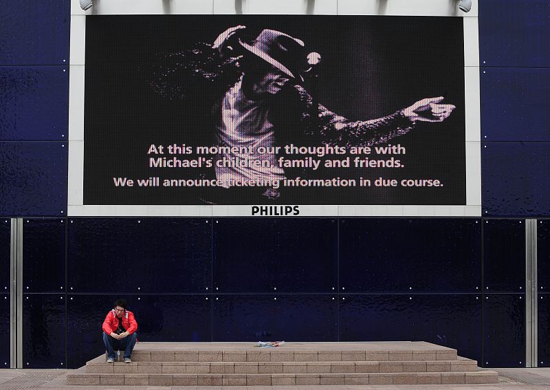 Un fan sentado bajo un cartel publicitario en Londres