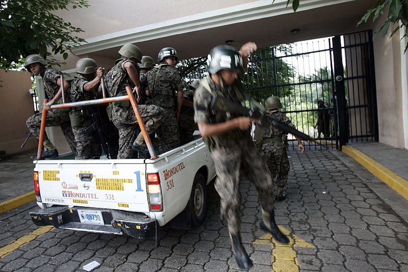 Honduran soldiers jump of a pick-up truck at the gates of the presidential palace in Tegucigalpa