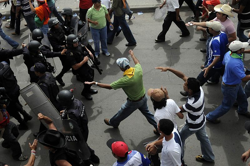 Seguidores del depuesto presidente de Honduras Manuel Zelaya se acercan al aeropuerto internacional de Toncontín mientras policías y soldados tratan de impedirlo.