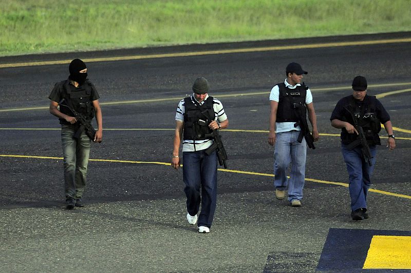 Miembros de las Fuerzas Armadas caminan armados por la pista de aterrizaje del aeropuerto de Toncontin, en Tegucigalpa, donde era esperado el avión del presidente depuesto.