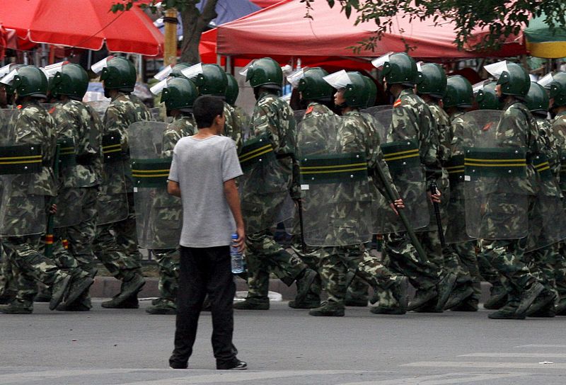 Un niño observa a un batallón de soldados chinos en Urumqi, donde se ha reforzado la seguridad tras los  enfrentamientos del domingo.