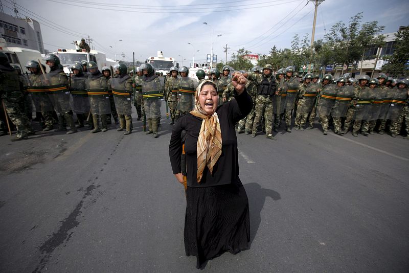 Una mujer musulmana  de etnia uigur protesta ante una columna de  antidisturbios durante una manifestación convocada en Urumqi