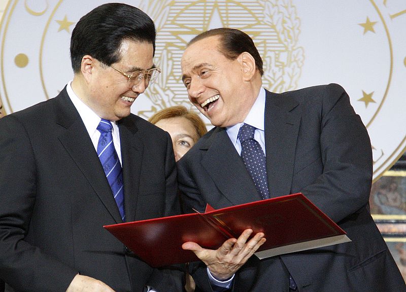 Italy's PM Berlusconi holds a document on economic and cultural exchanges with China's President Hu in Rome