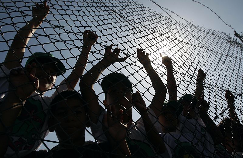 Palestinian children lean on a gate to the Rafah crossing in the southern Gaza