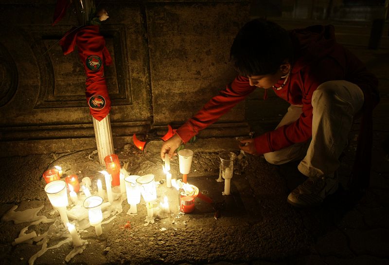 Un joven enciende una vela en el lugar donde murió el pasado viernes Daniel Jimeno cuando corría el encierro.