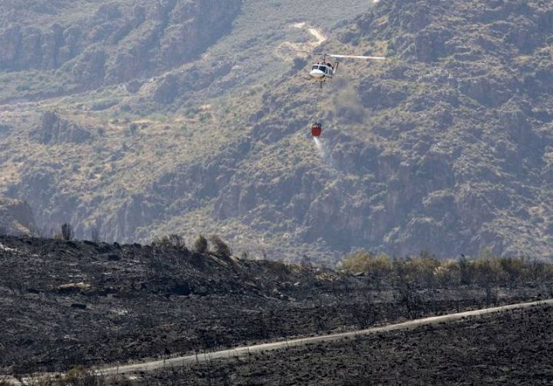 15/07/2009. Un helicóptero de los servicios de extinción sobrevuela la zona afectada por un incendio declarado en el parque natural de Sierra Cabrera, en Turre (Almería), y que ha calcinado ya más de 4.000 hectáreas de matorral. 