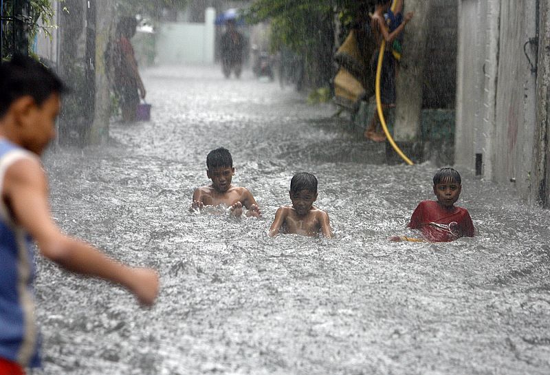 Children play in a flooded street caused by monsoon rains in Manila's suburban Las Pinas district