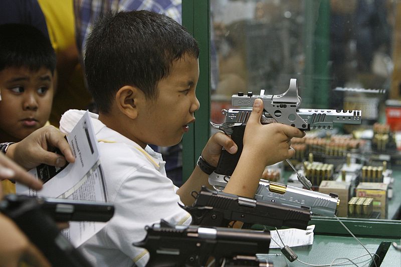 Un niño empuña un arma a la venta en la Feria Anual de armas