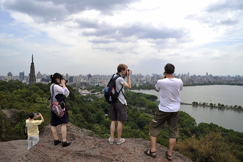 Algunos turistas toman fotos del West Lake en las montañas de Baoshi en la provincia china de Zhejiang.