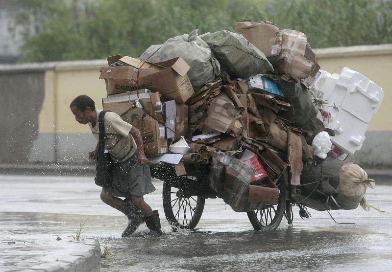 Un hombre chino tira de un carro cargado con materiales reciclables