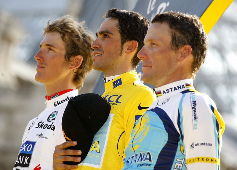 Astana rider Contador listens to his national anthem on the podium next to Saxo Bank rider Schleck and Astana rider Armstrong after the final stage of the Tour de France cycling race