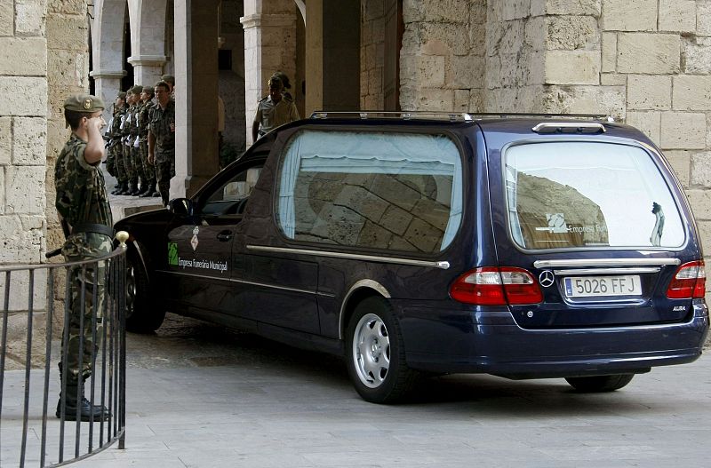 Uno de los dos coches fúnebres con los restos mortales de los dos guardias civiles asesinados ayer en la localidad balear de Calvià entra al Palacio de la Almudaina, donde ha quedado instalada la capilla ardiente.