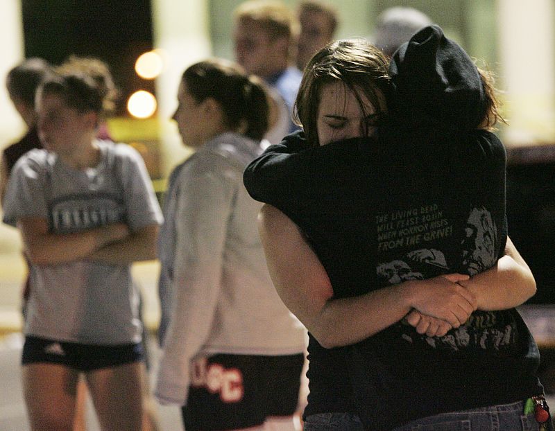 Two women hug in the parking lot outside the LA Fitness gym in Bridgeville after a shooting