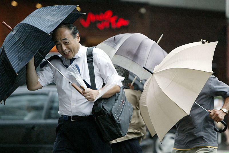 Pedestrians struggle with their umbrellas in strong winds and rain caused by typhoon Etau in Tokyo A..