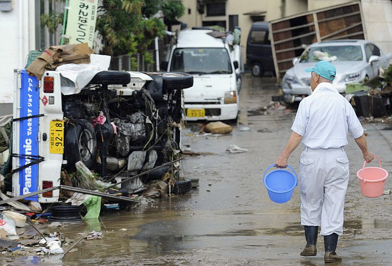 A man walks past a truck overturned by floodwaters in Sayo