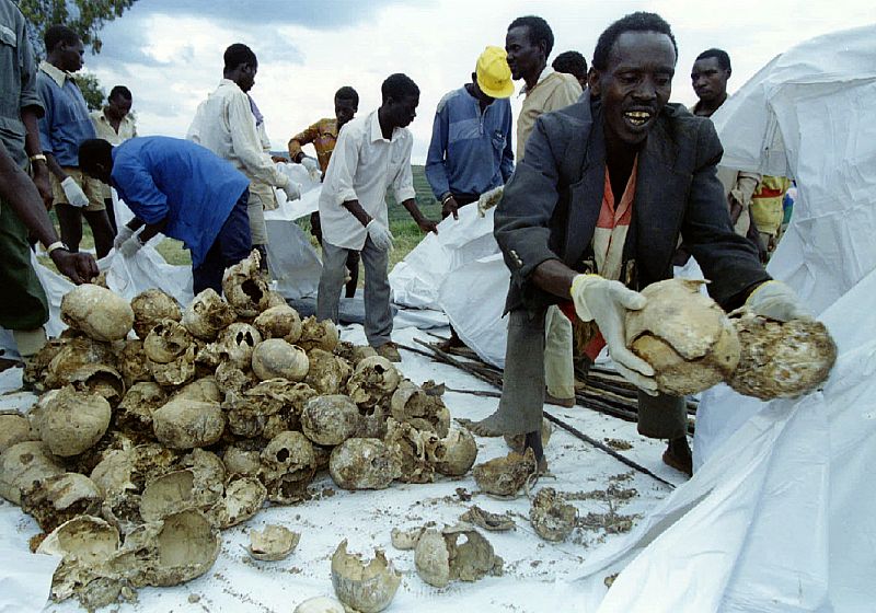 Rwandans place the skulls of several hundred Tutsi civilians into bags after a memorial for approxim..