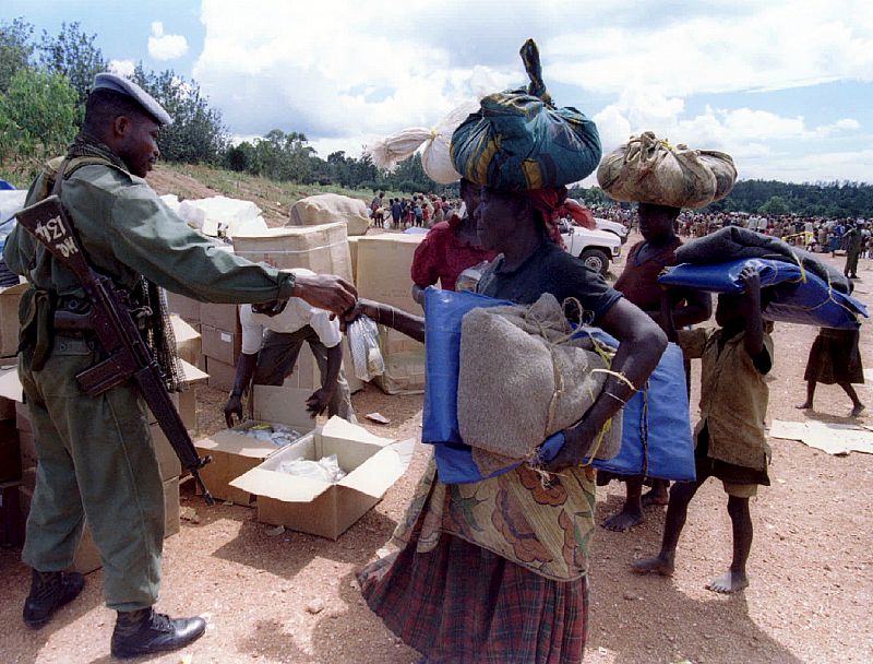 UN peacekeepers give food to Hutu refugees in a transit camp in a village in southern Rwanda April 2..