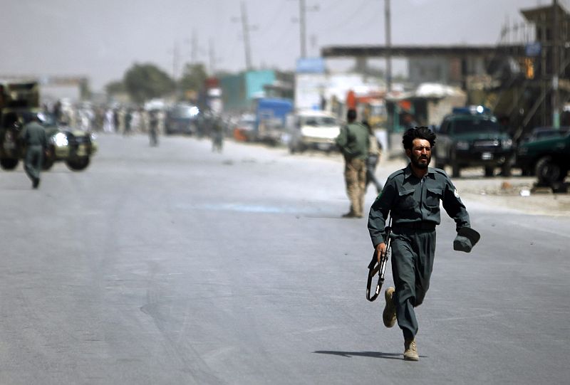 Afghan policeman runs away from the area of a suicide attack in Kabul