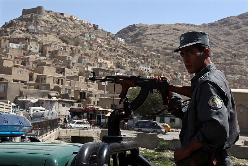 Afghan policemen keep watch atop a police vehicle after rockets hit Kabul