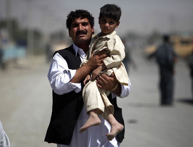 Afghan man carries a slightly wounded child from the area of a suicide attack in Kabul