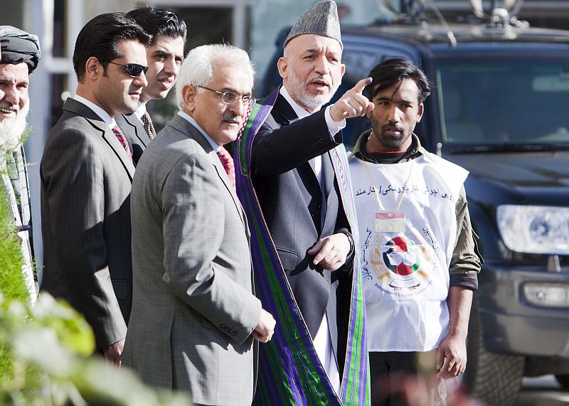 El presidente afgano Hamid Karzai y su ministro de Defensa, Spanta, salen del puesto de votación.