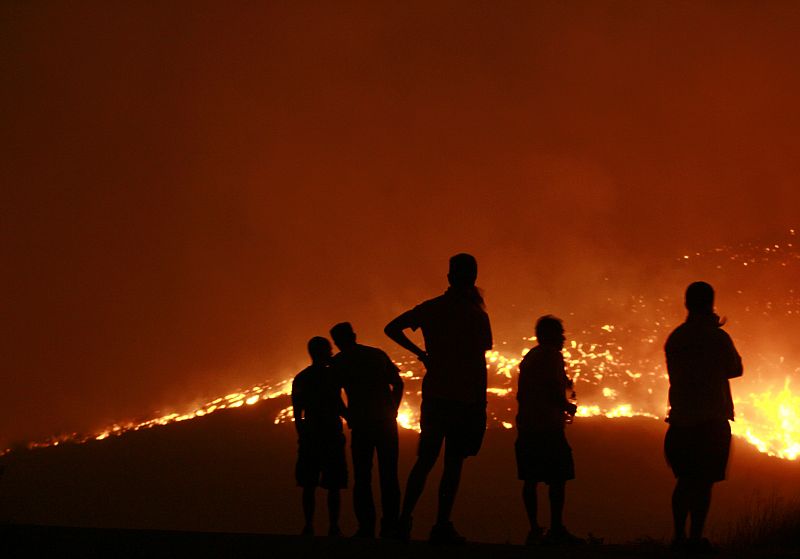 Residents watch a forest fire in the Anthousa suburb of Athens