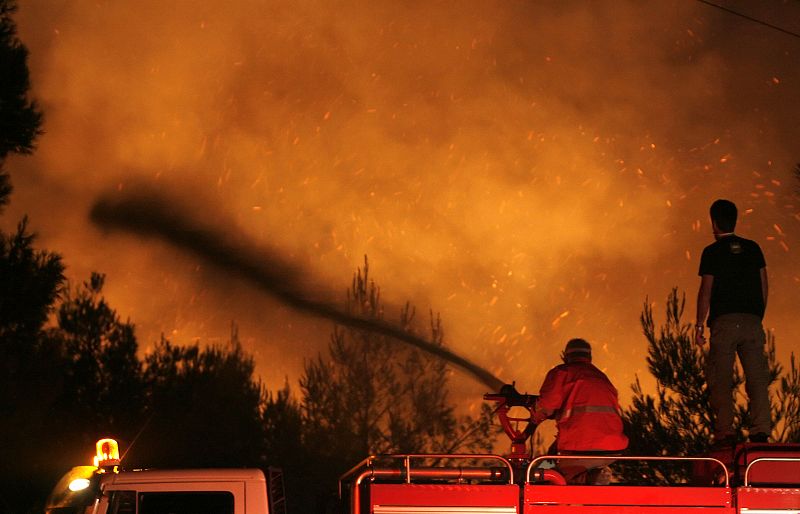 Firemen spray water at a forest fire on Dionysos mountain, north of Athens