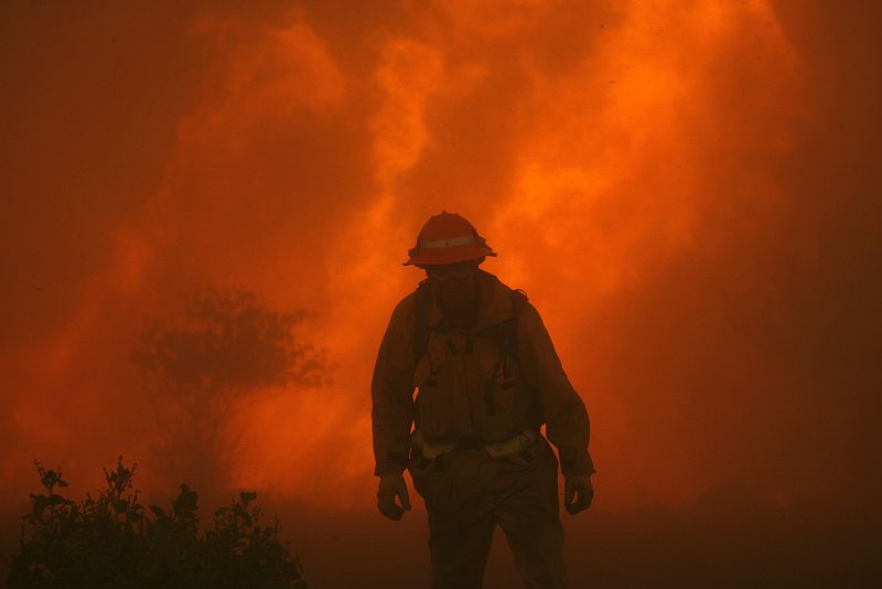 A Los Angeles County firefighter walks through thick smoke during the Station fire in the Acton area of Los Angeles