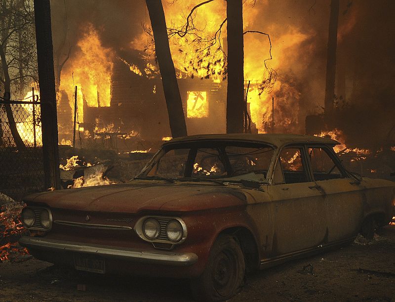 An unknown structure burns as a Chevy Corvair sits nearby during the Station Fire in the Big Tujunga Canyon area of Los Angeles