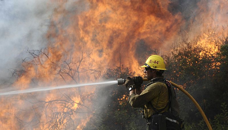 A firefighter aims water at the Station Fire in Angeles National Forest above the La Canada Flintridge area of Los Angeles
