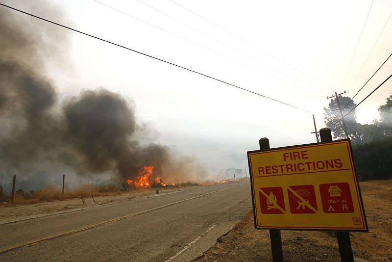 A fire burns on the side of the road during the Station Fire in Tujunga