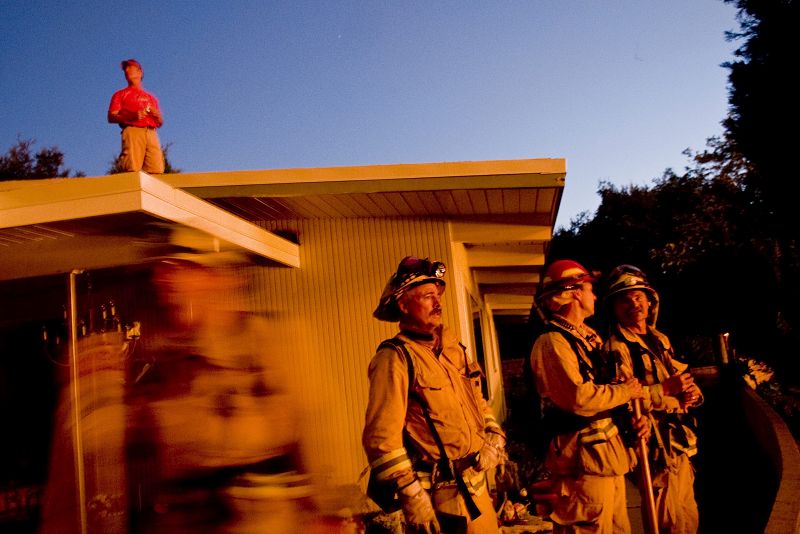 Un ciudadano observa el fuego desde el techo de la casa de su padre en La Crescenta, California.