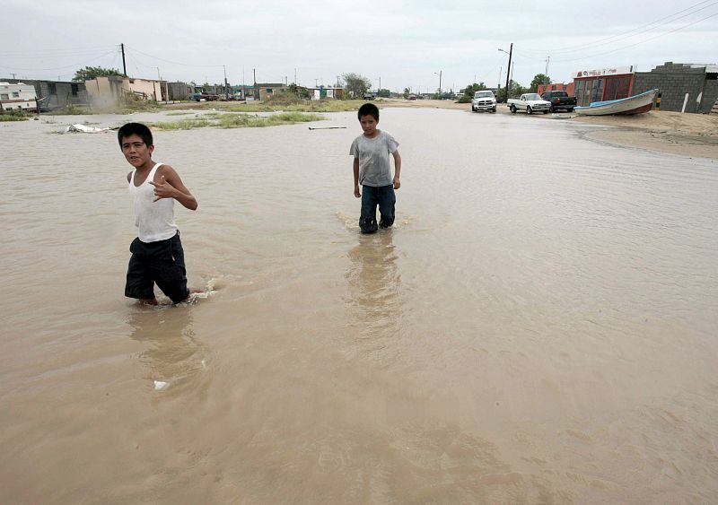 Children wade through a flooded street after Hurricane Jimena hit Puerto San Carlos