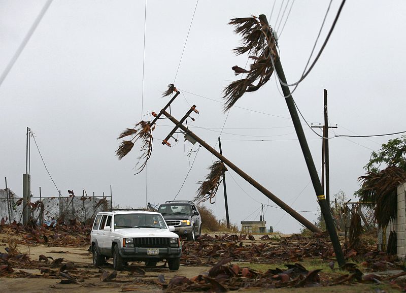 Cars drive under half-uprooted lightposts in Puerto San Carlos, Mexico's state of Baja California