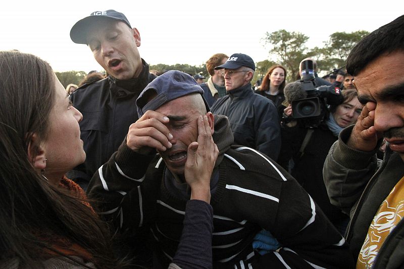 An illegal Afghan migrant is comforted by a volunteer as police evacuate him and others from an improvised camp in Calais