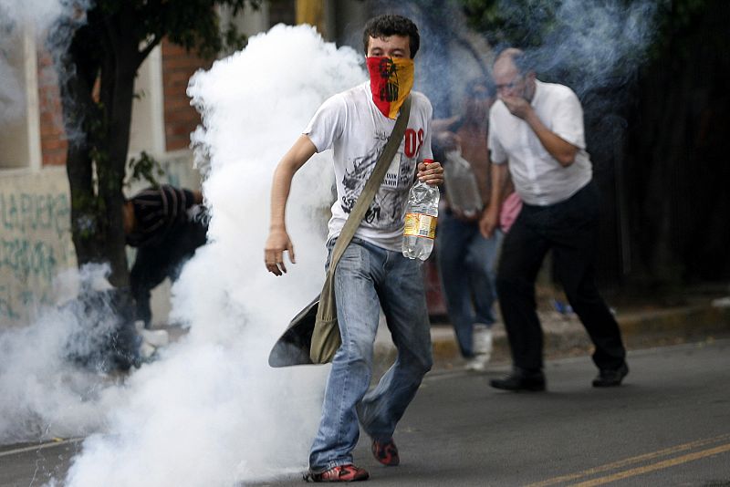 Supporters of ousted Honduras President Manuel Zelaya run amidst tear gas fired by police, near the Brazilian embassy in Tegucigalpa