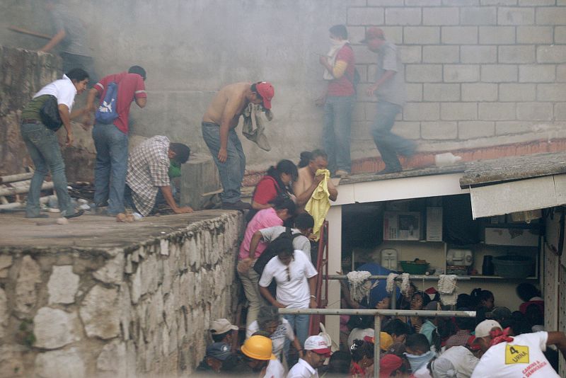 Supporters of ousted Honduras President Manuel Zelaya are seen on a roof outside the Brazilian embassy after police fired tear gas, in Tegucigalpa