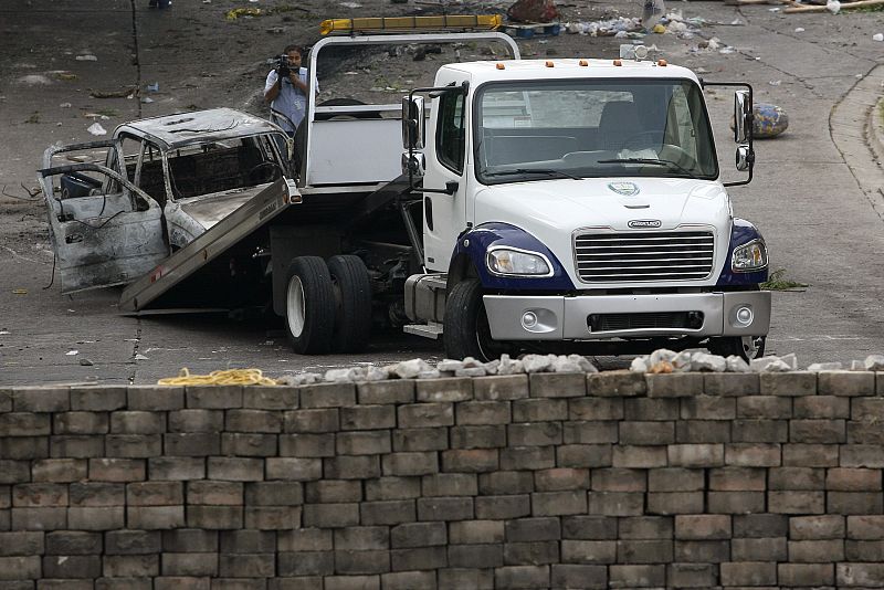 A truck is used to remove a car destroyed during clashes between police and supporters of ousted Honduras President Zelaya, near the Brazilian embassy in Tegucigalpa
