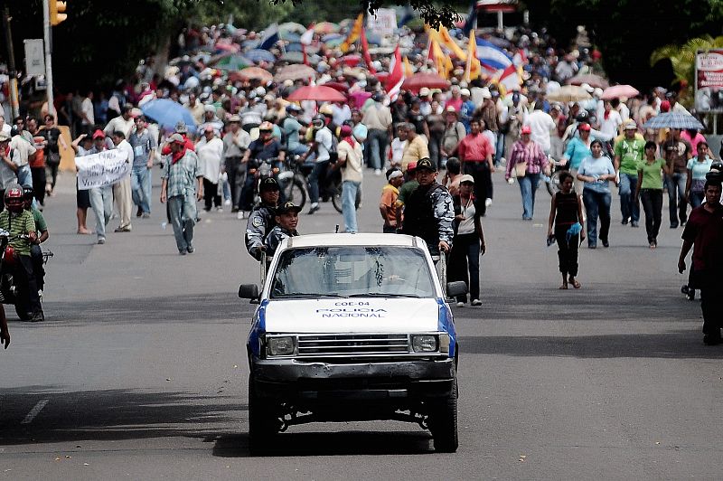 Policías hondureños pasan frente a una marcha de simpatizantes del depuesto presidente hondureño