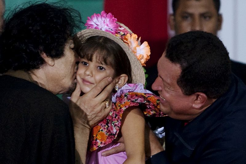 Libya's leader Gaddafi kisses a girl held by Venezuela's President Chavez during ceremony in Margarita Island