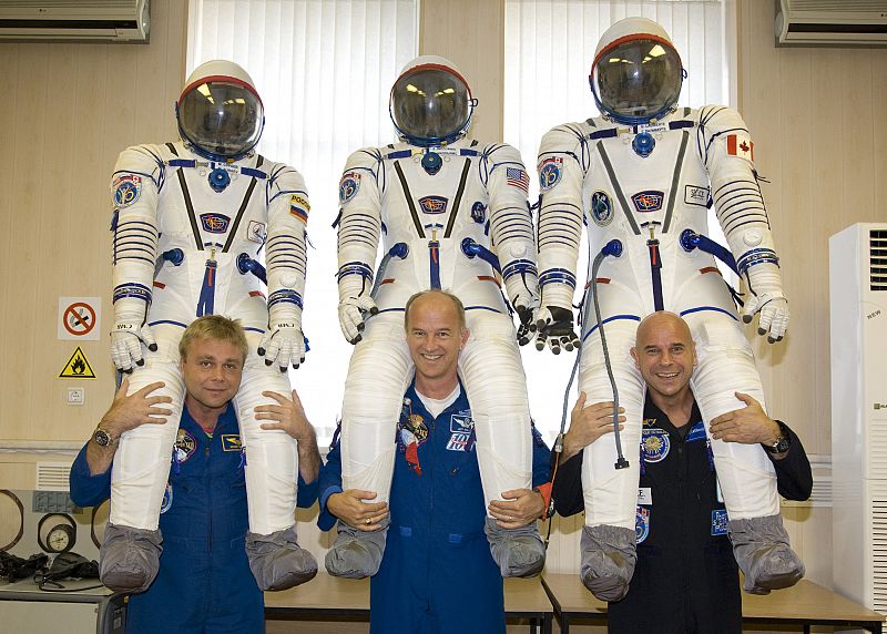 Laliberté posa junto al cosmonauta ruso Maxim Surayev (L) y el astronauta americano Jeffrey Williams, sus compañeros de viaje, con sus respectivos trajes espaciales