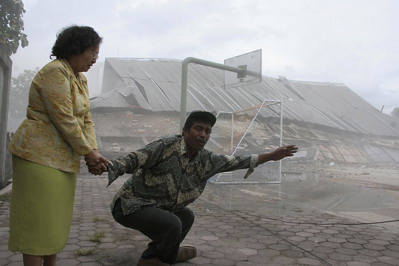 Teachers hold each other in front of a collapsed university building after an earthquake hit Padang