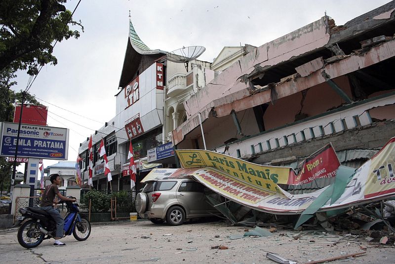 A man sits on a motorcycle outside a collapsed shopping mall after an earthquake hit Padang