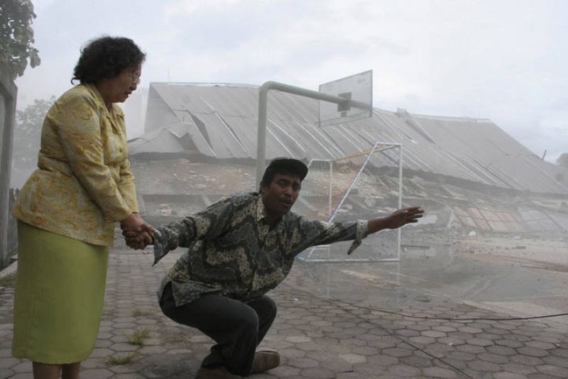 Teachers hold each other in front of a collapsed university building after an earthquake hit Padang